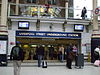 A white building with a dark blue, rectangular sign reading "LIVERPOOL STREET UNDERGROUND STATION" in white letters all under a white sky