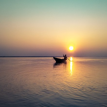 Silhouette of a fisherman on boat during sunset at Brahmaputra River