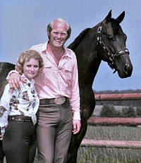 Un homme et une femme posent devant un cheval à la campagne.