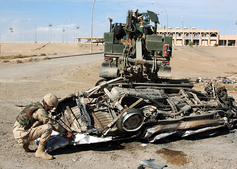 File:US Navy 041118-N-4388F-006 Construction Mechanic 2nd Class Thomas Tupling, assigned to Naval Mobile Construction Battalion Four (NMCB-4), attaches a tow cable to a demolished car prior to removing it from a street in Fallujah,.jpg