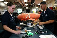 Vérification à bord de l'USS Kitty Hawk (CV-63) d'un kit de survie pour aviateurs avec un radeau de sauvetage, à destination d'un équipage de C-2A Greyhound.