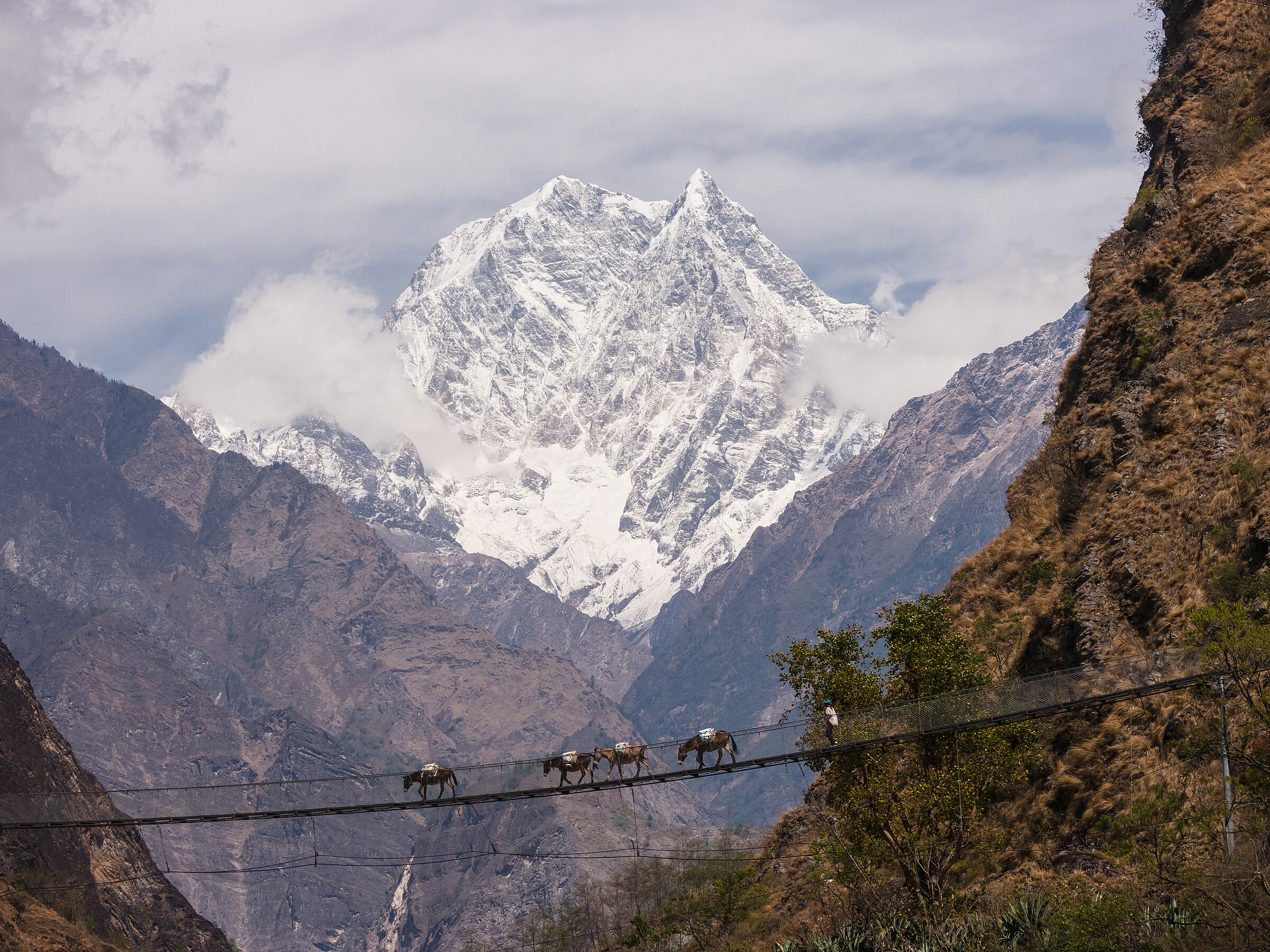 Nilgiri South (6,839m) forms an impressive backdrop to a large suspension bridge over the Kali Gandaki river near Tatopani. © Frank Jones