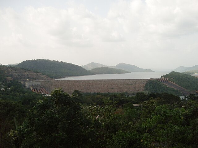 Aerial view of a large rock structure located in a forest between the mountains, large pipes and a cloudy sky