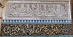 Close-up of Arabic calligraphy in carved stucco and painted tile