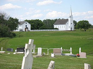 Blick vom Friedhof auf das Pfarrhaus und die Kirche