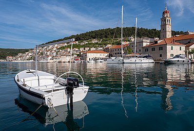 Boat at the Pučišća harbour, with the Saint Jerome Church tower in the background, Croatia