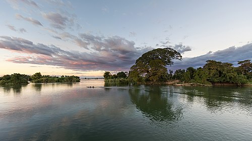 Pirogue running on the Mekong at sunset with pink clouds in Don Det Laos