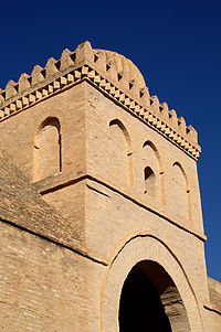 Fotografia da parte superior do quarto pórtico da fachada oeste.  É decorado com arcos cegos quebrados.  O arco mediano da fachada frontal é perfurado por uma pequena baía.