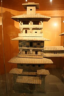 A painted ceramic architectural model--found in a Han tomb--depicting an urban residential tower with verandas, tiled rooftops, dougong support brackets, and a covered bridge extending from the third floor to another tower Pottery tower 6a.JPG