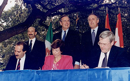 NAFTA signing ceremony, October 1992. From left to right: (standing) President Carlos Salinas de Gortari (Mexico), President George H. W. Bush (U.S.), and Prime Minister Brian Mulroney (Canada).