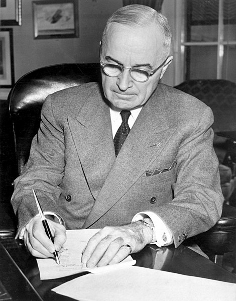 Harry S. Truman signing a proclamation declaring a national emergency that initiates U.S. involvement in the Korean War