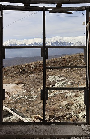 A view of Šar Mountains through a wooden window frame of an abandoned building