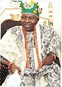 Oba Oladele Olashore is show in traditional Yoruba attire sitting on a chair