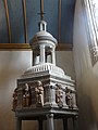 Église Notre-Dame de Bodilis, partie supérieure des fonts baptismaux du XVIème siècle en pierre, de forme hexagonale, orné de statues polychromes en kersantite attribuées à Roland Doré.