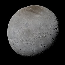 Photographie de haute résolution d'un corps gris foncé où de nombreux cratères et zones plus sombres sont observables.