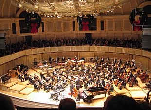 The Chicago Symphony Orchestra performing with a jazz group. The string sections are at the front of the orchestra, arrayed in a semicircle around the conductor's podium. Chicago Symphony Orchestra 2005.jpg