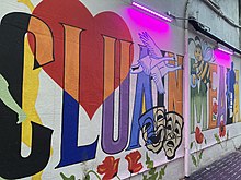 Mural in Clonmel with the Irish name of the town; note the bee and honey. Clonmel mural with Irish name.jpg