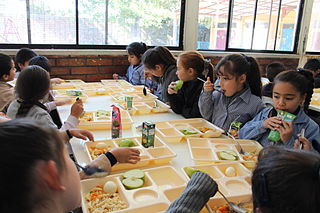  Foto de niñas y niños comiendo en una mesa.    