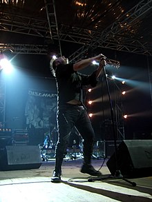 Discharge performing in Rome in 2006. The distinctive lettering of the band's name can be seen in the banner at the back of the stage. Discharge2.jpg