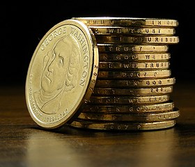 Dollar coin stack showing "IN GOD WE TRUST" on edge