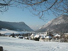 Village de montagne sous la neige avec une pente parcourue de traces de luges et autres.