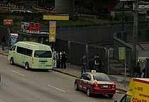 Flere mennesker venter på fortovet i Puerto Aéreo Boulevard, ved siden af ​​stationens indgang.