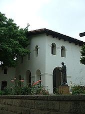 The entrance lobby and belfry of the Mission San Luis Obispo de Tolosa. A statue of Fray Junipero Serra stands outside the church. MissionSanLuisEntrance.jpg
