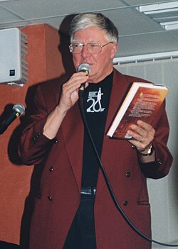 Olov Svedelid håller upp en bok och talar i en mikrofon