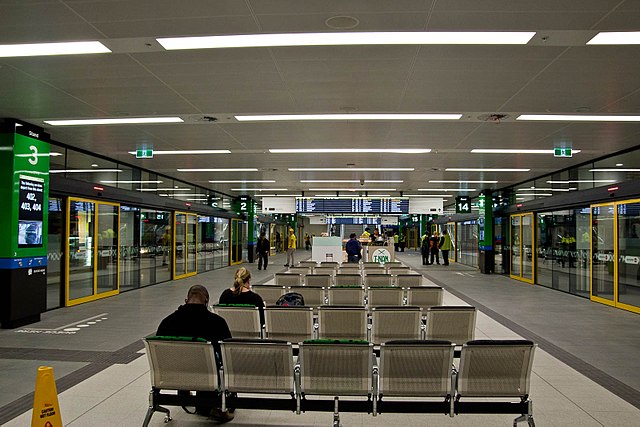 Underground waiting area surrounded by glass windows into the busway