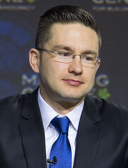 Poilievre wearing a black suit and blue tie