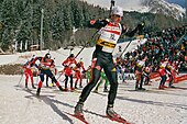 A man skiing, with a pack of skiers behind him.