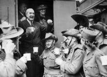 Fotografía de Bruce sonriente tintineando vasos con soldados uniformados en la parte trasera de un vagón