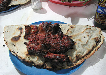 Tlayuda con falda, a tlayuda folded in half and topped with grilled skirt steak