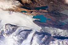 Two small icebergs at right clearly retain fragments of the moraine (rock debris) that forms a dark line along the upper surface of the glacier. The inclusion of the moraine illustrates how land-based rocks and sediment are carried by ice. Upsala Glacier, Argentina.jpg