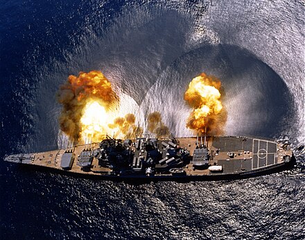 USS Iowa firing her guns broadside (1984). Note that intervening structures such as the bridge tower would prevent all of the guns from being focused directly forward or aft.