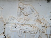 A carving of the family of Marija and Petar Skuljevic exhibiting sadness over their deaths Grob Marije i Petra Shkuljvitsha na srbskom praoslavnom groblju u Dubrovniku.jpg