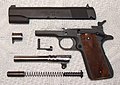 A M1911A1 pistol disassembled and showing the locking grooves on the barrel.