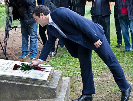 Alexis Tsipras laying down red roses at the Kaisariani Memorial.