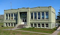 Photograph of the Antelope School, a two-story concrete building with a symmetrical facade and tall windows on the upper level, set in a broad, treeless landscape