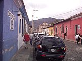 אופי רחוב באנטיגואה שבגואטמלה, הבנוי מבתים נמוכים ופשוטים בעיצובם וצבועים בצבעים שונים. מבני הציבור השונים מודגשים על רקע העיצוב העירוני האחיד.