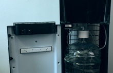 Bottom load water dispenser revealing 5-gallon bottle, with cabinet opened Bottom Load Water Dispenser.png