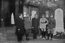 Thomas Bentley Mott and others, some in military uniform, stand in a row in front of a monument.