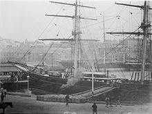 Cutty Sark moored in a port, possibly Sydney. Another clipper can be seen in the background. Cutty Sark (ship, 1869) - SLV H91.250-165.jpg