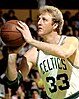 Larry Bird, wearing the Boston Celtics jersey, is trying to shoot a basketball.