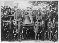 The Liberty Bell on a wagon; a number of people, including policemen, pose with it.