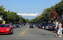 An intersection in downtown Los Altos, with features like tree-lined sidewalks, diagonal parking, small shops, and banners advertising community events