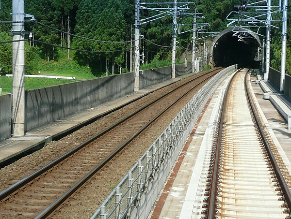 The Airport branch line (left) running alongside the 1,435 mm (4 ft 8+1⁄2 in) gauge Keisei Sky Access Line (right) in July 2010