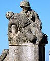 Soldado sujetando a un compañero caído, a la derecha del monumento