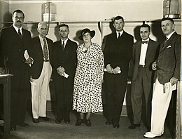 monochrome photograph of six men and a woman, standing
