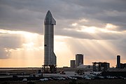 Starship SN9 sitting on the launch pad with the build site in the background ahead of its test flight.